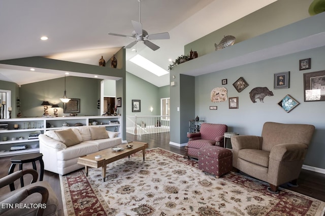 living room with hardwood / wood-style flooring, high vaulted ceiling, a skylight, and ceiling fan