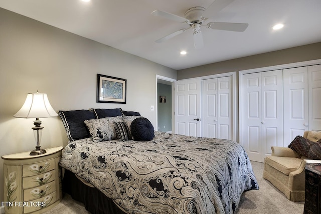 bedroom featuring ceiling fan, light colored carpet, and multiple closets