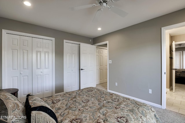 bedroom featuring ceiling fan, light colored carpet, and multiple closets