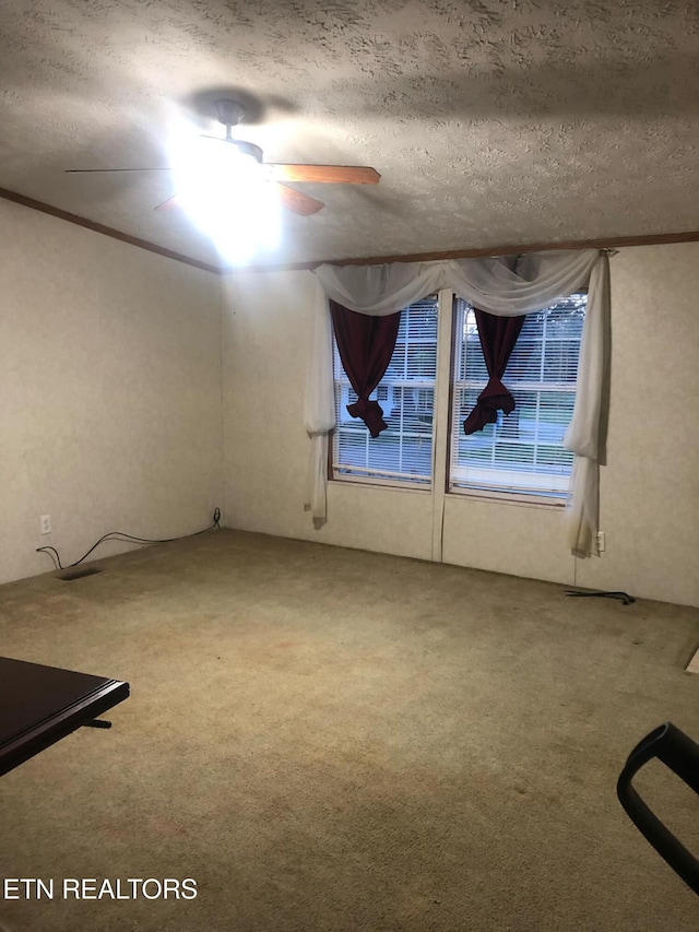 carpeted empty room featuring ceiling fan, a textured ceiling, and crown molding