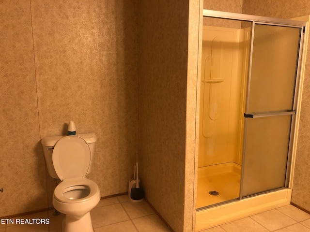 bathroom with tile patterned flooring, an enclosed shower, and toilet