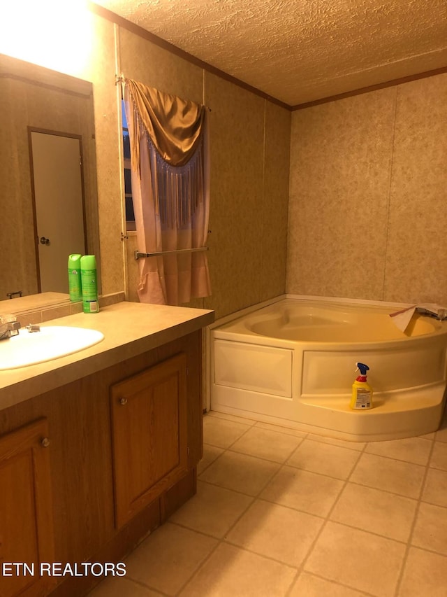 bathroom with tile patterned flooring, a bath, a textured ceiling, and vanity