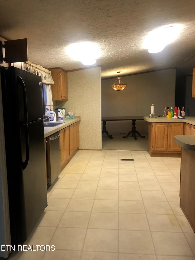 kitchen with black fridge, sink, a textured ceiling, stainless steel dishwasher, and hanging light fixtures