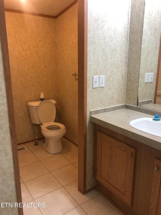 bathroom with ornamental molding, toilet, vanity, and tile patterned floors