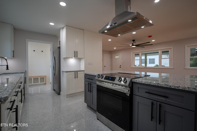 kitchen featuring white cabinetry, ceiling fan, light stone countertops, island range hood, and appliances with stainless steel finishes