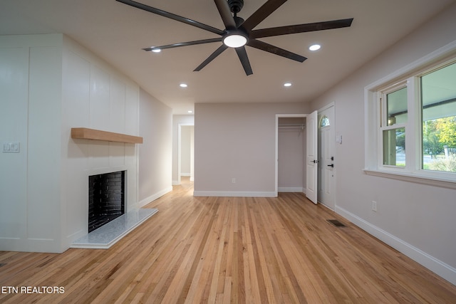 unfurnished living room with ceiling fan, light wood-type flooring, and a fireplace