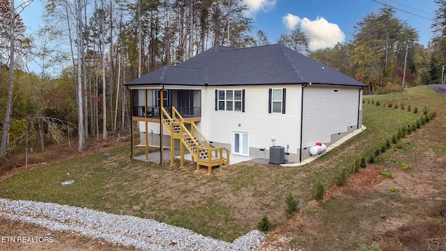 rear view of house with central AC unit, a sunroom, and a yard