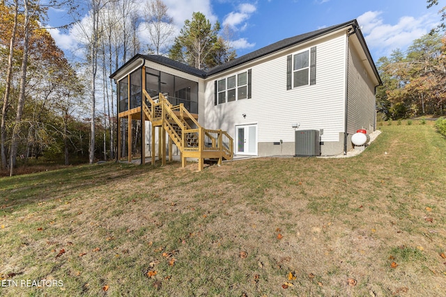 rear view of house with a sunroom, a yard, and central AC