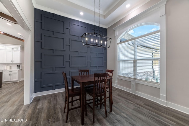 dining room featuring dark wood-type flooring, a notable chandelier, and crown molding