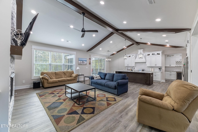 living room featuring light wood-type flooring, vaulted ceiling with beams, and a healthy amount of sunlight