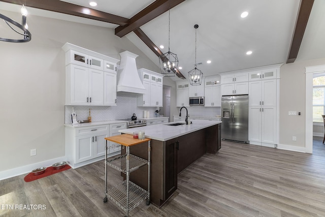 kitchen with white cabinets, premium range hood, an island with sink, and stainless steel appliances