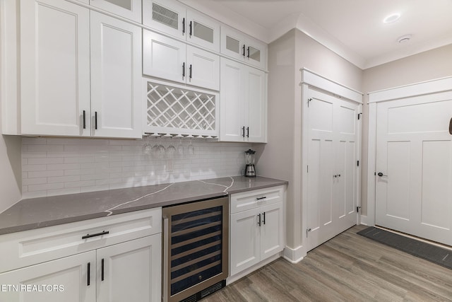 bar with wine cooler, backsplash, light hardwood / wood-style floors, and white cabinets