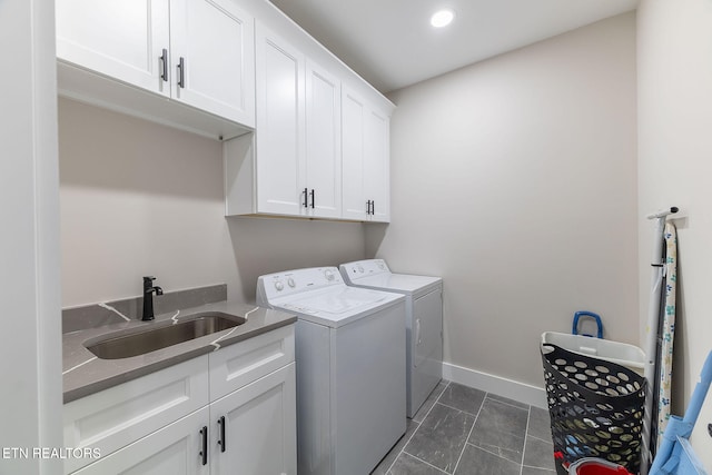 laundry room with washing machine and clothes dryer, cabinets, sink, and dark tile patterned floors