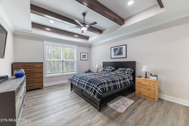 bedroom with crown molding, hardwood / wood-style floors, ceiling fan, and a raised ceiling