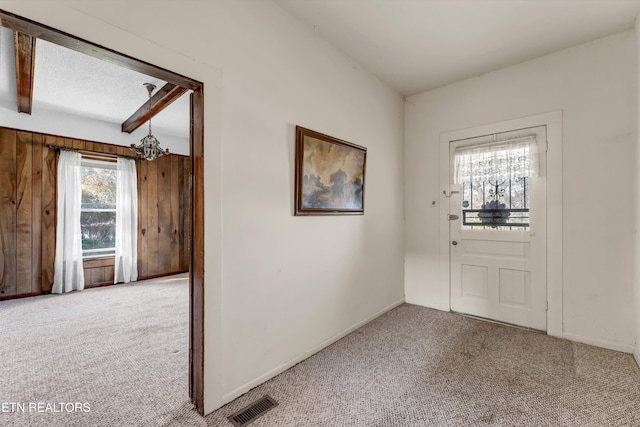 foyer entrance featuring beamed ceiling and carpet floors