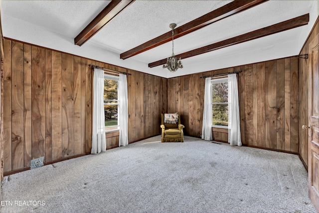 unfurnished room featuring a textured ceiling, wooden walls, and beam ceiling