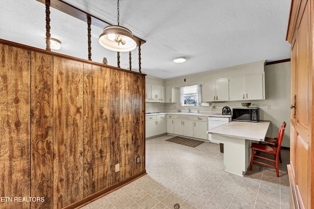 kitchen featuring a textured ceiling, hanging light fixtures, sink, white cabinets, and dishwasher