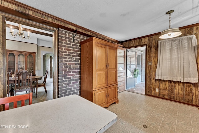 bedroom featuring ornamental molding, a textured ceiling, access to exterior, wood walls, and a chandelier