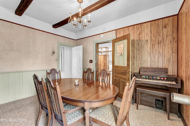 dining room featuring wooden walls, a notable chandelier, and beam ceiling