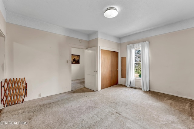 unfurnished bedroom with light colored carpet and a closet