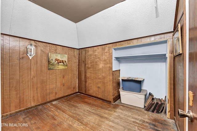 unfurnished bedroom with a closet, wood walls, a textured ceiling, and wood-type flooring