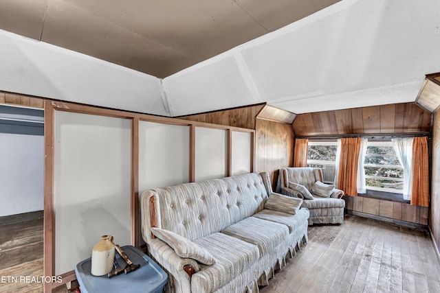 sitting room with wood walls, lofted ceiling, and light hardwood / wood-style floors