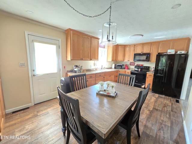 kitchen with hardwood / wood-style floors, plenty of natural light, black appliances, and decorative light fixtures