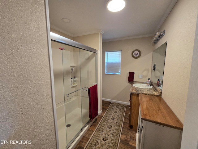 bathroom featuring an enclosed shower, vanity, hardwood / wood-style flooring, and crown molding