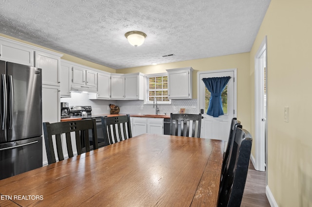 dining area with a textured ceiling, sink, and dark wood-type flooring