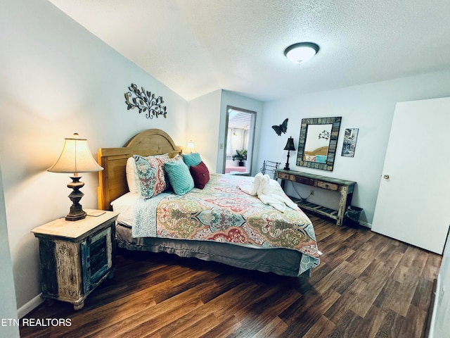 bedroom with dark wood-type flooring, a textured ceiling, and vaulted ceiling