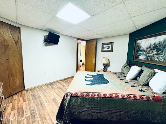 bedroom with a drop ceiling and hardwood / wood-style flooring