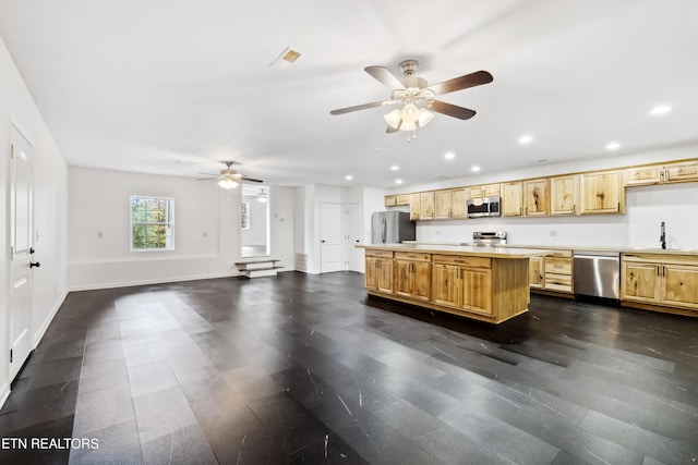 kitchen with light brown cabinetry, stainless steel appliances, ceiling fan, and a center island