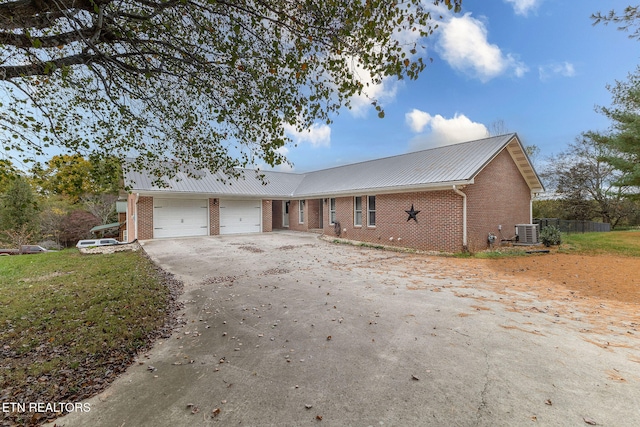 ranch-style home featuring central AC unit and a garage