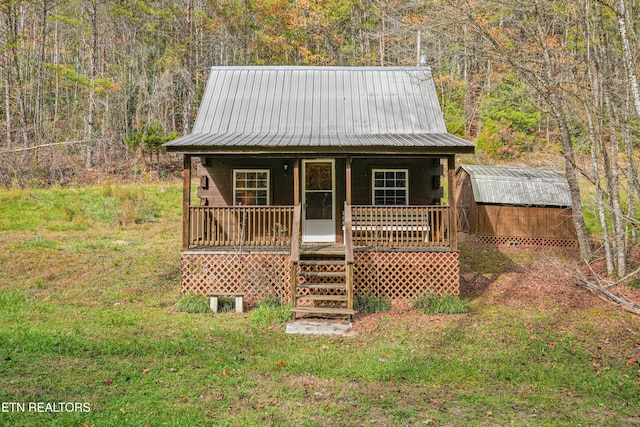 view of front of property featuring a storage shed, a front yard, and a porch