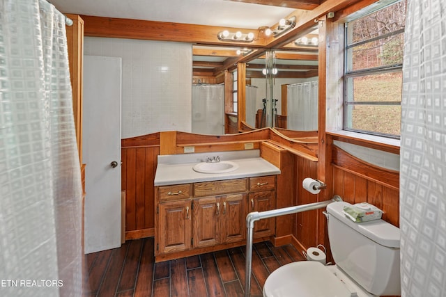 bathroom with vanity, toilet, hardwood / wood-style floors, and wood walls