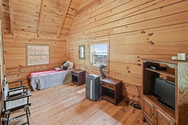 bedroom with beam ceiling, wooden walls, light wood-type flooring, and multiple windows