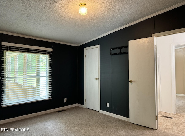 unfurnished bedroom featuring a textured ceiling, light colored carpet, crown molding, a closet, and lofted ceiling