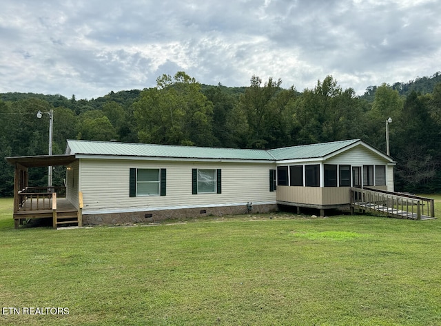 view of front of property featuring a front lawn, a wooden deck, and a sunroom