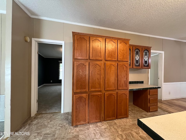 kitchen featuring a textured ceiling, light colored carpet, and crown molding