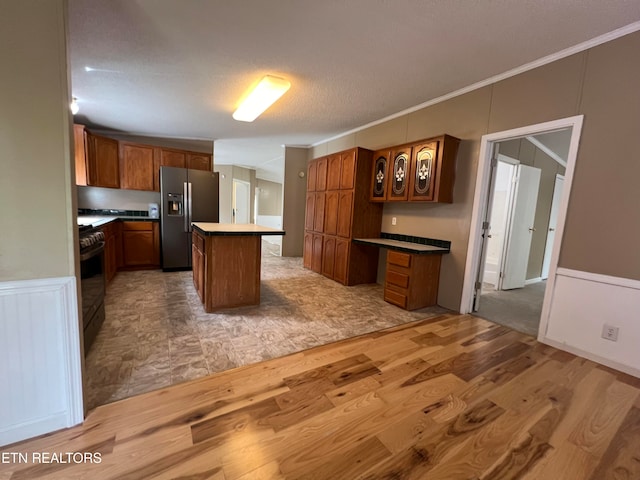 kitchen with black range with electric stovetop, a center island, stainless steel refrigerator with ice dispenser, light hardwood / wood-style floors, and ornamental molding