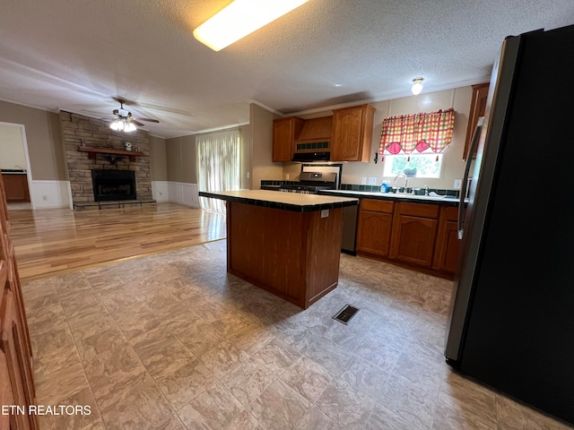 kitchen with a kitchen island, light wood-type flooring, a textured ceiling, and appliances with stainless steel finishes