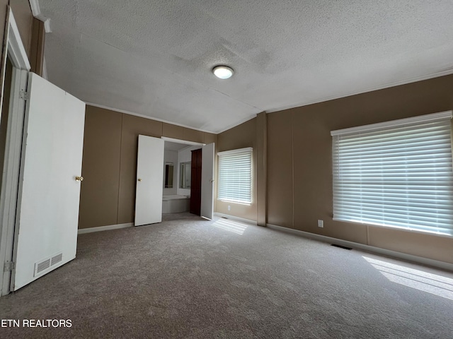 unfurnished room featuring carpet, a textured ceiling, and vaulted ceiling