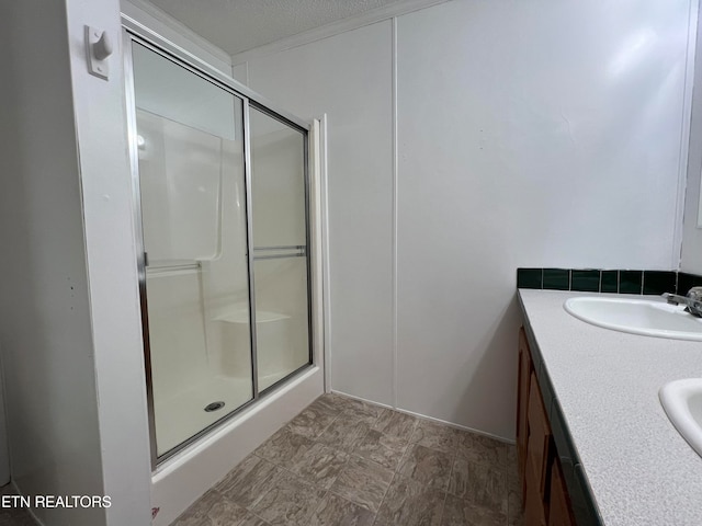 bathroom with a textured ceiling, vanity, and a shower with door