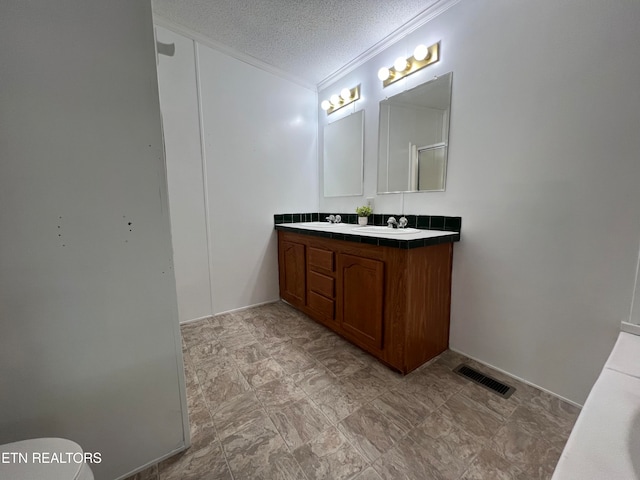 bathroom featuring vanity, a textured ceiling, and ornamental molding