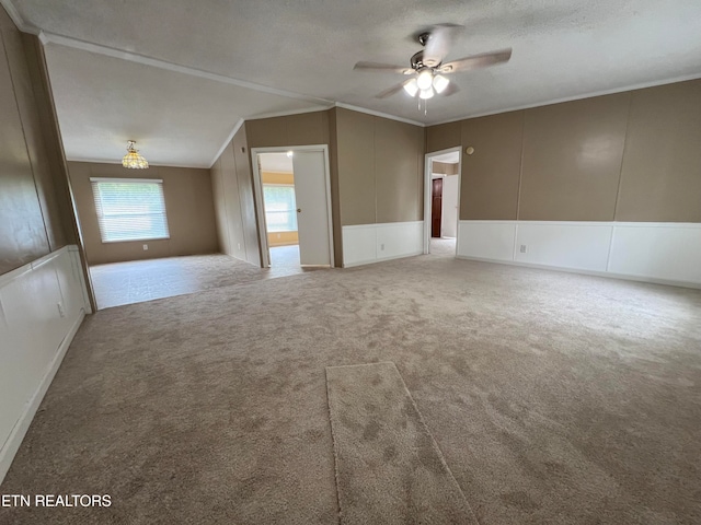 unfurnished room featuring a textured ceiling, vaulted ceiling, ceiling fan, crown molding, and carpet floors