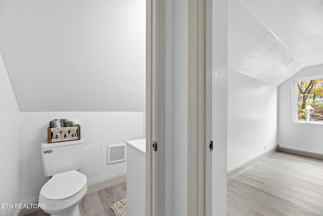 bathroom featuring hardwood / wood-style flooring, toilet, and lofted ceiling