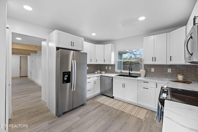 kitchen featuring white cabinetry, sink, light wood-type flooring, and appliances with stainless steel finishes