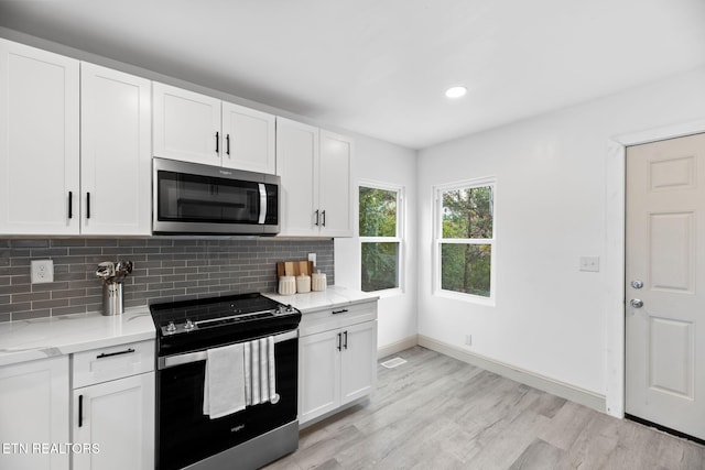 kitchen featuring light hardwood / wood-style flooring, appliances with stainless steel finishes, light stone counters, and white cabinets