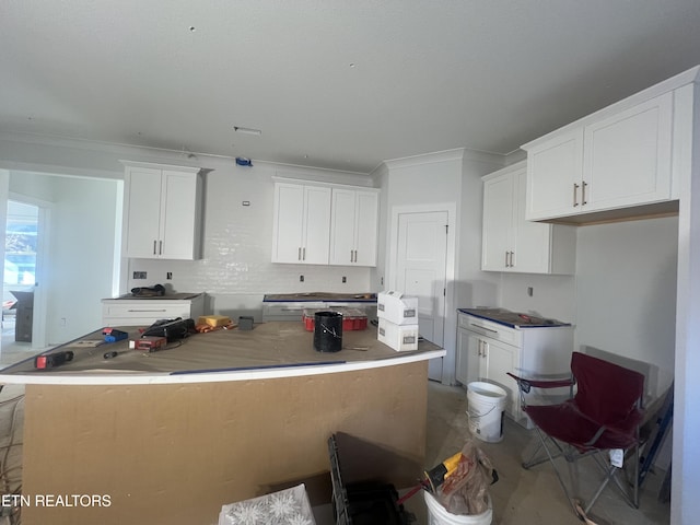 kitchen with white cabinetry, concrete flooring, and a kitchen island