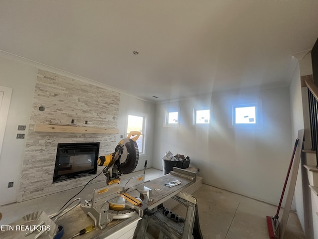 living room with crown molding and a stone fireplace